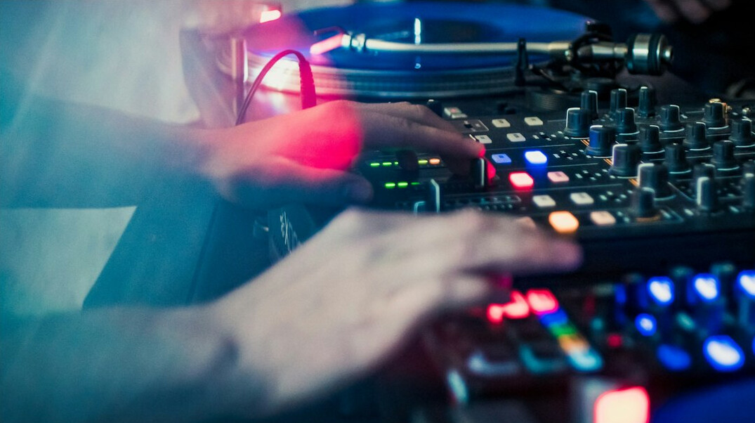 Hands adjusting sliders on a broadcast audio mixing console